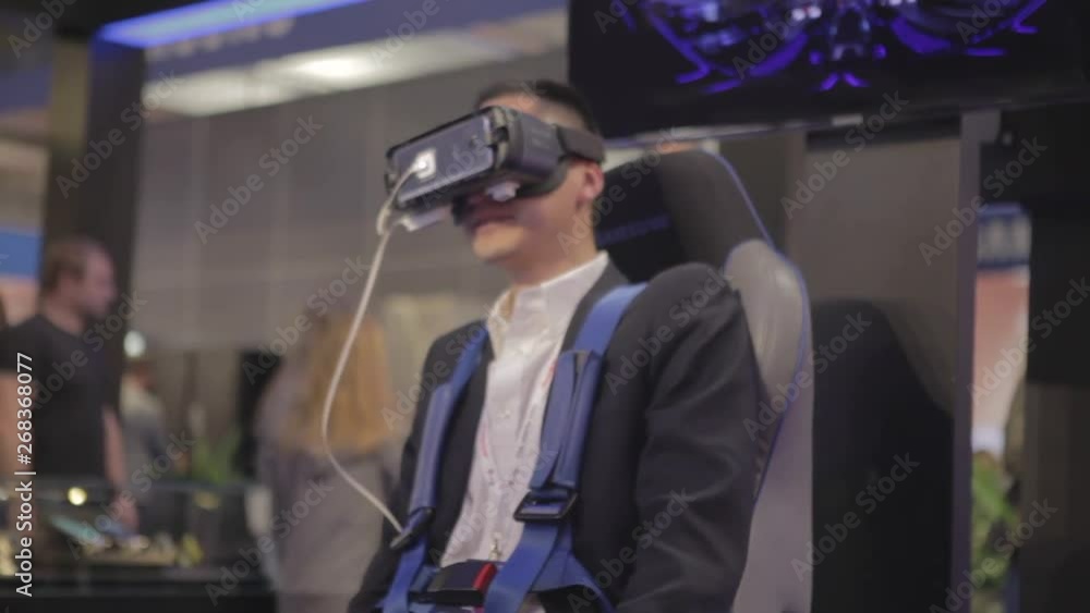 Man of Asian appearance, sitting on a chair with a headset and a virtual reality controller, uses virtual reality. Man of Asian appearance, sitting on a chair with a headset and a virtual reality controller, uses virtual reality.