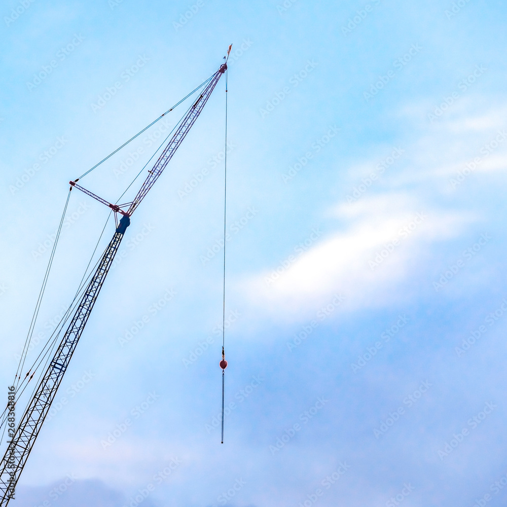 Clear Square A lifting crane viewed against a beautiful blue sky filled with cottony clouds Clear Square A lifting crane viewed against a beautiful blue sky filled with cottony clouds