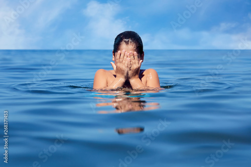 Caucasian little boy wiping his face in the sea