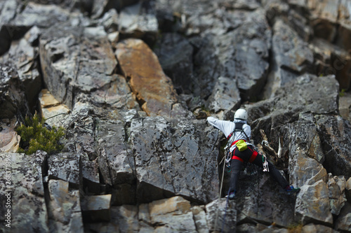 The girl climber climbs up the rocks. Tilt-Shift effect.