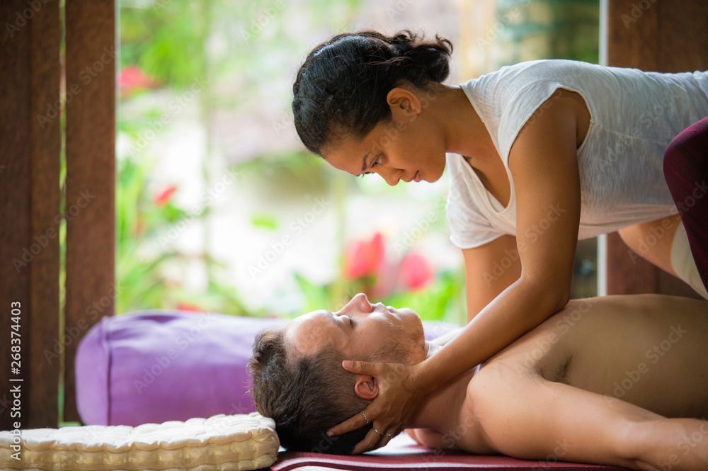 young beautiful and exotic Asian Indonesian therapist woman giving  traditional Thai massage to man relaxed at tropical wellness spa in healthy  natural lifestyle Stock Photo | Adobe Stock