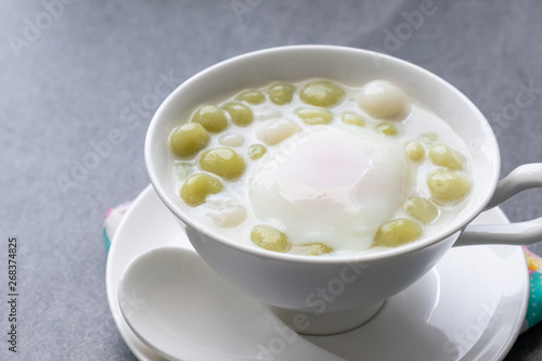 Pandan Thai glutinous rice balls (Bua Loi) in white bowl on table,Boiled egg.