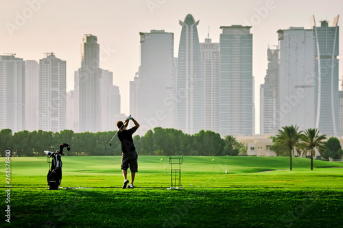 Photography golf player playing golf on the on the grass field against the skyscraper buildi