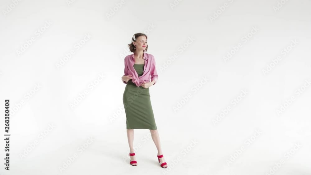 Beautiful brunette girl model with short hair on a white background unbuttons her shirt posing in the Studio. Beautiful brunette girl model with short hair on a white background unbuttons her shirt posing in the Studio.