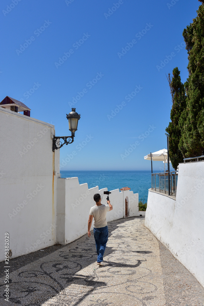 Man with gimbal for smartphone, walking through the streets of a Mediterranean town