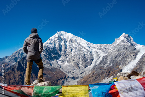 Bilde på lerret Trekker looking towards himalayas peaks of Langtang with prayer flags in foregro