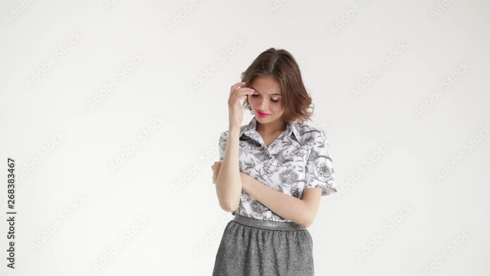 Model sexy girl in shirt and skirt posing on white background.The brunette twists her skirt. Model sexy girl in shirt and skirt posing on white background.The brunette twists her skirt.