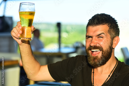 Handsome barman holding a pint of beer. Man holds glass of beer. Enjoy in pub. Beer time.