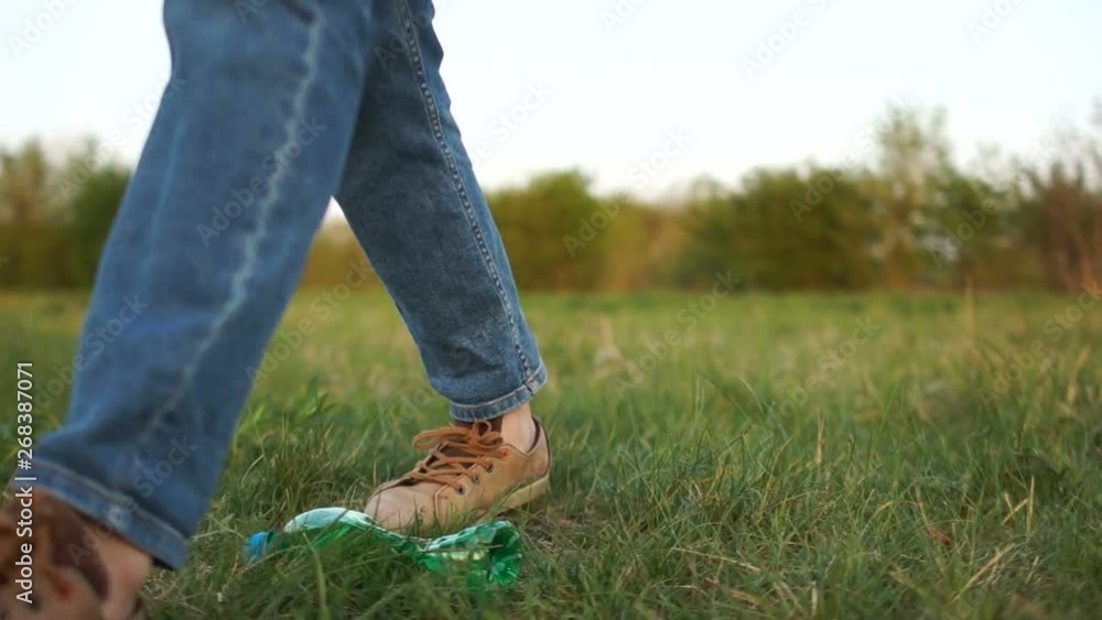 Close-up of a woman throwing a plastic bottle on the grass and leaving. The problem of domestic waste, stop plastic Close-up of a woman throwing a plastic bottle on the grass and leaving. The problem of domestic waste, stop plastic
