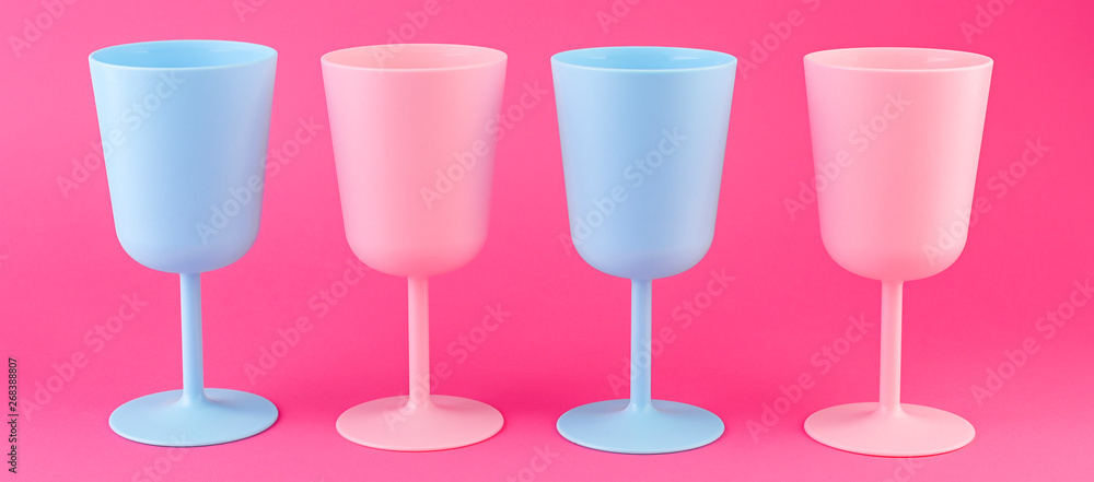 Colored plastic picnic utensils in bright colors. Glasses of blue and pink. Eco dishes. Banner.