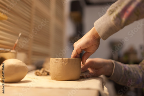 Female potter works with ceramic at his workshop. Young woman work inside  © supersomik
