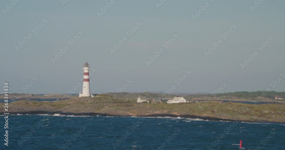 Lighthouse on a rocky island, choppy sea, blue sky Lighthouse on a rocky island, choppy sea, blue sky