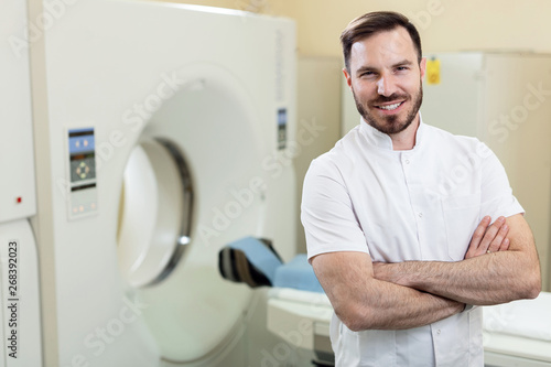 Billede på lærred Smiling male radiologist in front of MRI scanner at clinic.