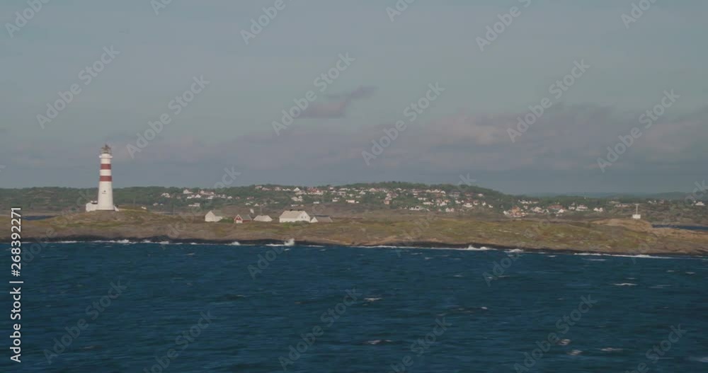 Lighthouse on a rocky island, choppy sea, blue sky