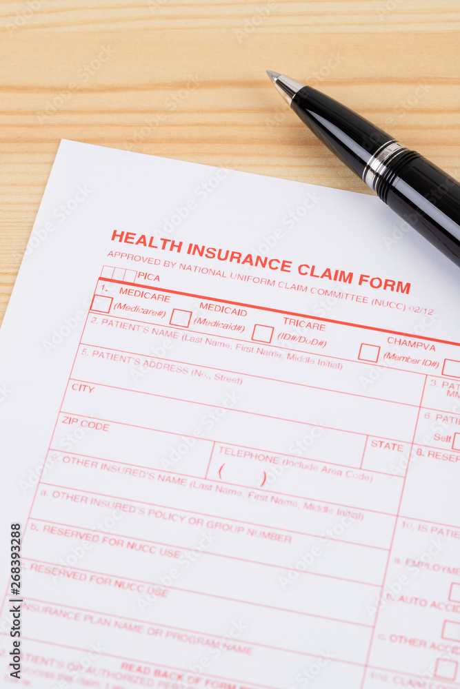 Health insurance claim form with pen on wooden desk Health insurance claim form with pen on wooden desk