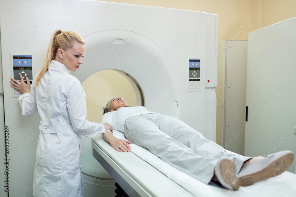 Radiologist preparing a patient for MRI scan procedure in medical examination room. Radiologist preparing a patient for MRI scan procedure in medical examination room.