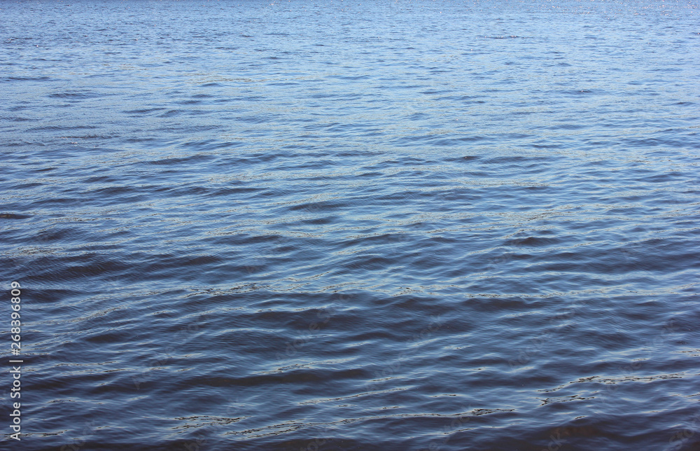 Blue water background with ripples and splashes on empty vibrant river surface on sunny day Blue water background with ripples and splashes on empty vibrant river surface on sunny day