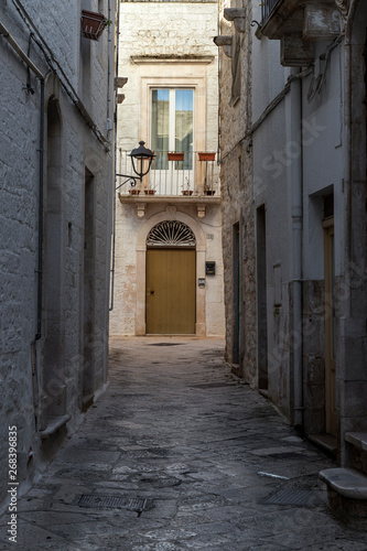 Una calle estrecha encalada de blanco en un pueblo medieval de la regi  n de Puglia en Italia