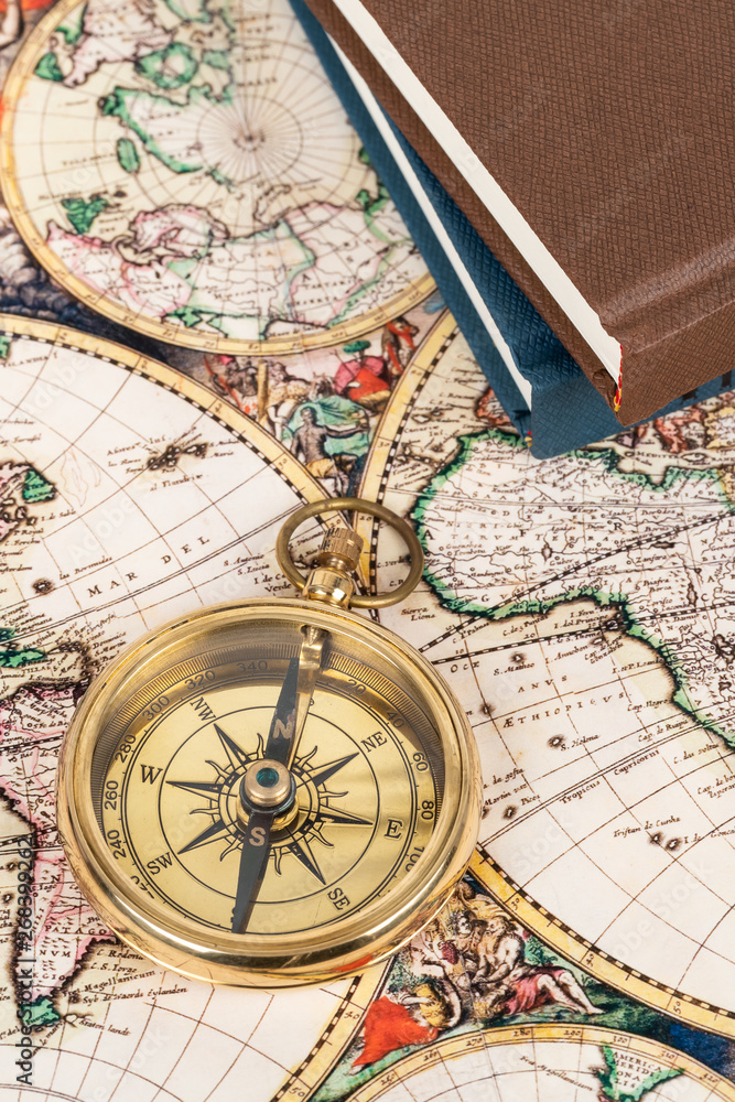 Compass on vintage ancient map with book, concept for direction transportation and travel