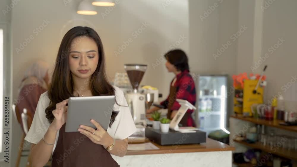 asian waiter with apron close up holding tablet pc smiling in her coffee shop asian waiter with apron close up holding tablet pc smiling in her coffee shop