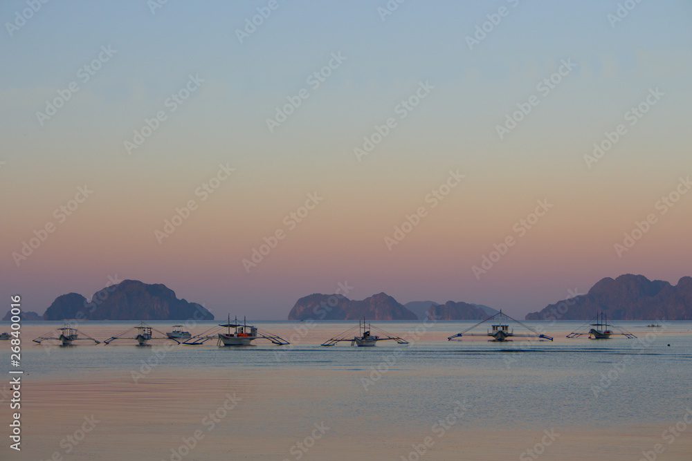 Fototapeta premium Calm morning on Philippines island with traditional boats. Sunrise on Palawan, Philippines. Tropical isles in morning dusk. Asian landscape. Summer vacation. Travel and transport concept.