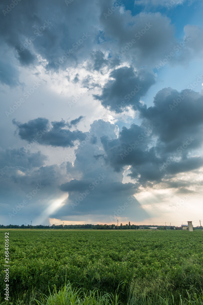 Clouds with light rays and stormy weather over agriculture fields Clouds with light rays and stormy weather over agriculture fields