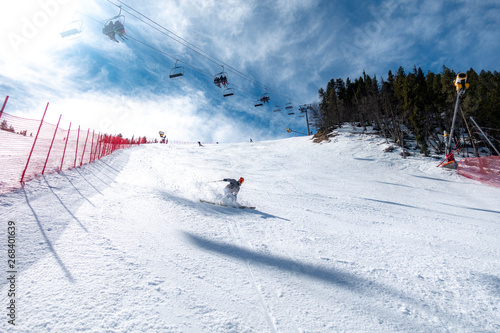 Skier carving with chair lift and other skiers in background