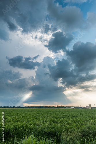 Clouds with light rays and stormy weather over agriculture fields