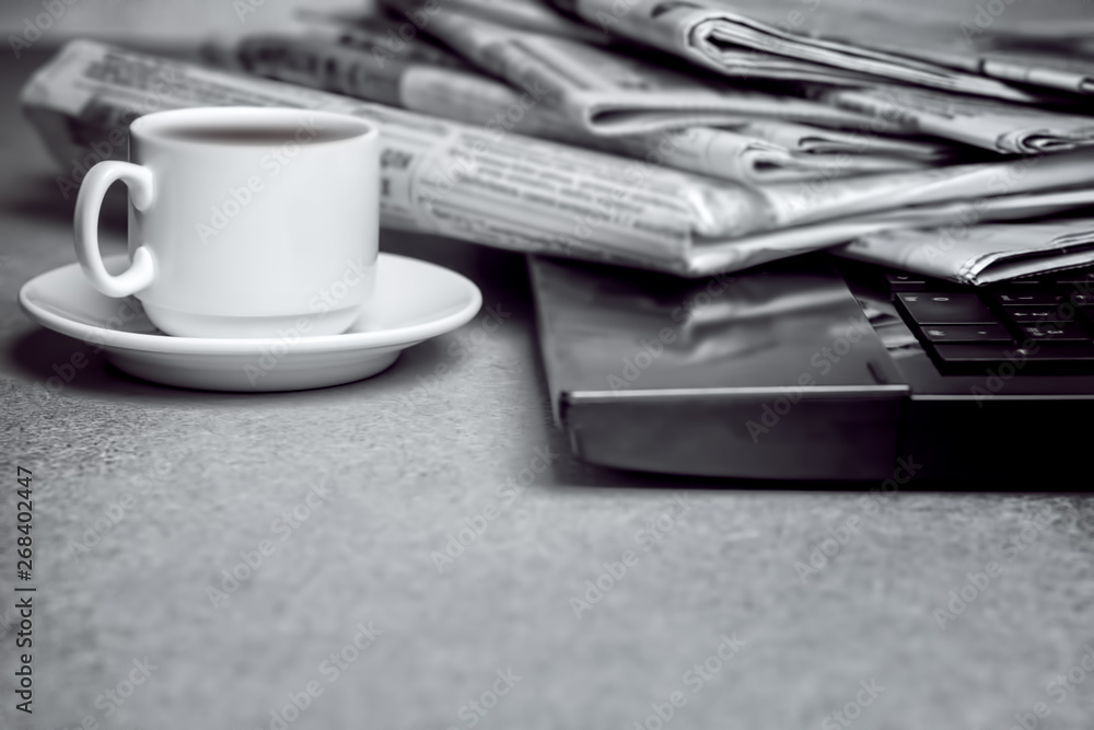 The concept of news. Folded stack of Newspapers on laptop, Cup of coffee The concept of news. Folded stack of Newspapers on laptop, Cup of coffee