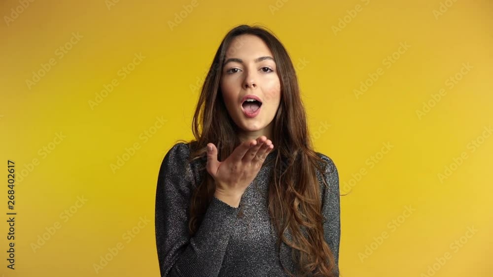 Pretty flirting woman sending kiss to you on yellow background Pretty flirting woman sending kiss to you on yellow background