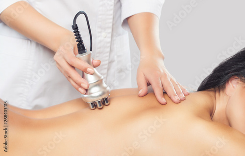 The doctor does the Rf lifting procedure on the back of a woman in a beauty parlor. Treatment of overweight and flabby skin.