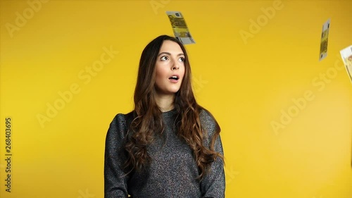 Surprised happy woman standing under money rain banknotes falling down