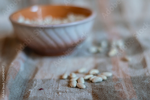White beans in a clay deep plate and on a linen tablecloth, soft focus