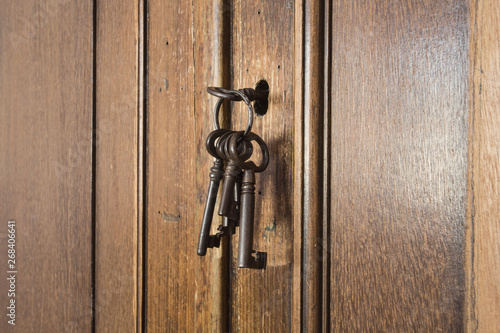 Old rusty keys inside a keyhole of an old antique closet. vintage design