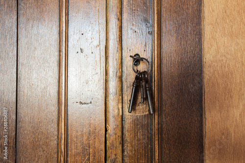 Old rusty keys inside a keyhole of an old antique closet. vintage design