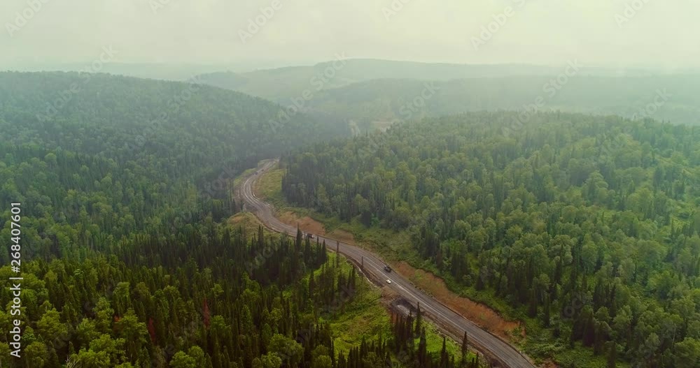 Panorama aerial view on road in forest. Aerial view of Dumpers on country road in forest. View from the drone at Taiga with lots of machinery trucks Panorama aerial view on road in forest. Aerial view of Dumpers on country road in forest. View from the drone at Taiga with lots of machinery trucks