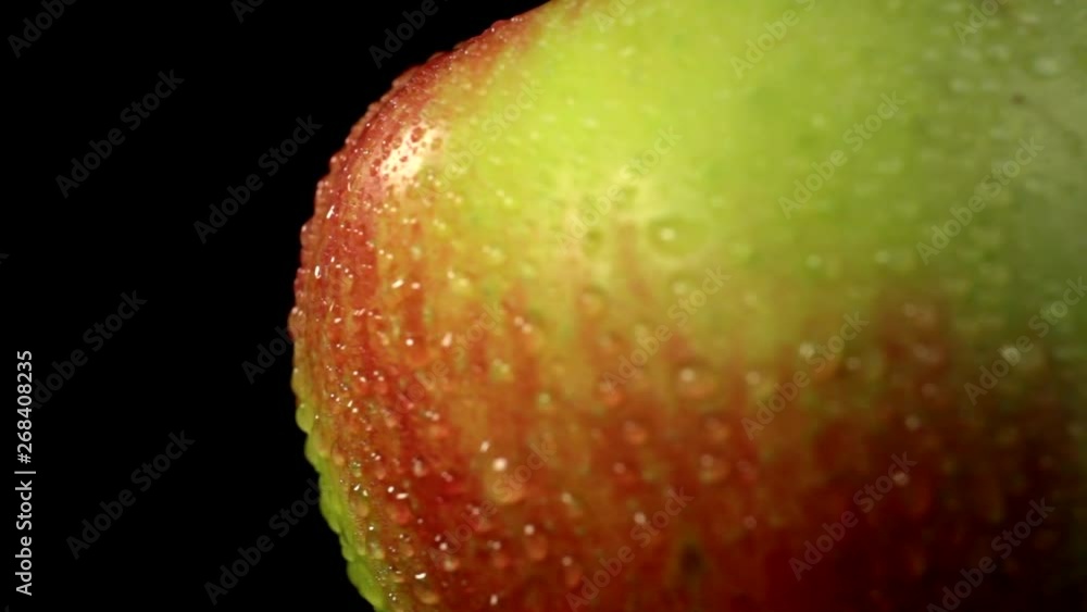 Apple skin in extreme macro close up with a rotational camera move. Red apple with water droplets on a black background. Apple skin in extreme macro close up with a rotational camera move. Red apple with water droplets on a black background.