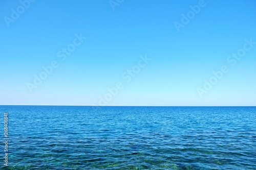 Beautiful seascape on sunny day with wind patterns on calm azure water and clear blue sky without clouds. Ocean view with horizon, background with a lot of copy space for text.
