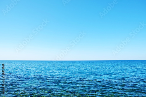 Beautiful seascape on sunny day with wind patterns on calm azure water and clear blue sky without clouds. Ocean view with horizon, background with a lot of copy space for text.