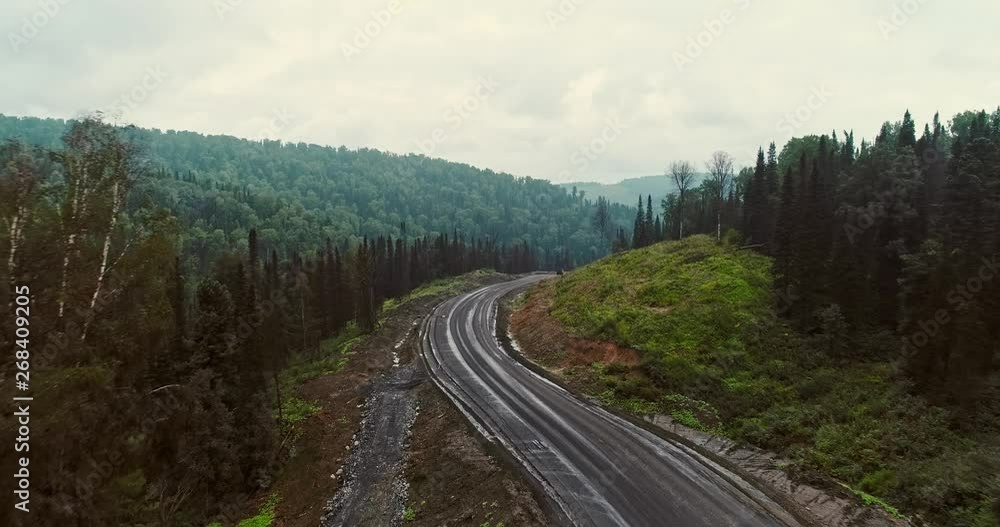 Panorama aerial view on road in forest. Aerial view of Dumpers on country road in forest. View from the drone at Taiga with lots of machinery trucks Panorama aerial view on road in forest. Aerial view of Dumpers on country road in forest. View from the drone at Taiga with lots of machinery trucks