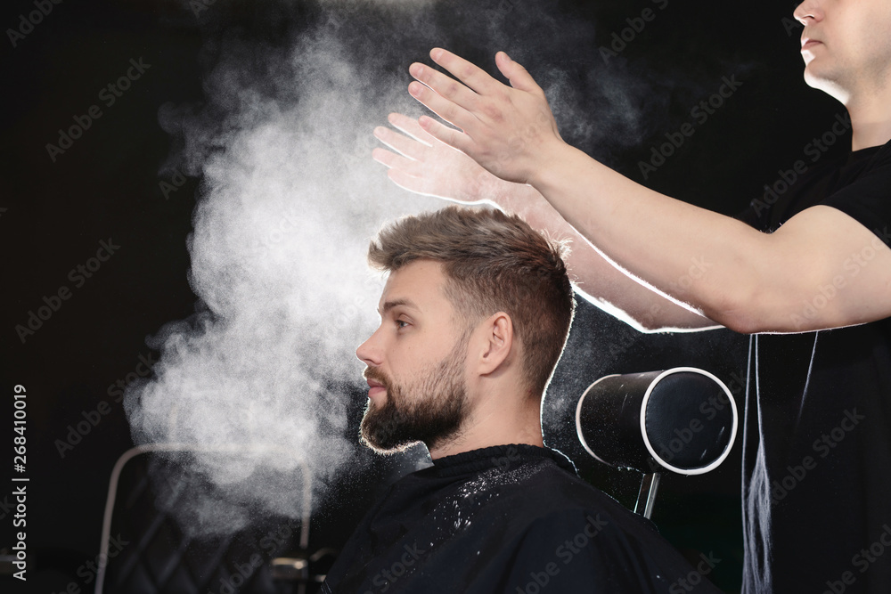 Professional hairdresser barber using talcum powder for his client hair  sitting in a barber chair on black background Stock Photo | Adobe Stock