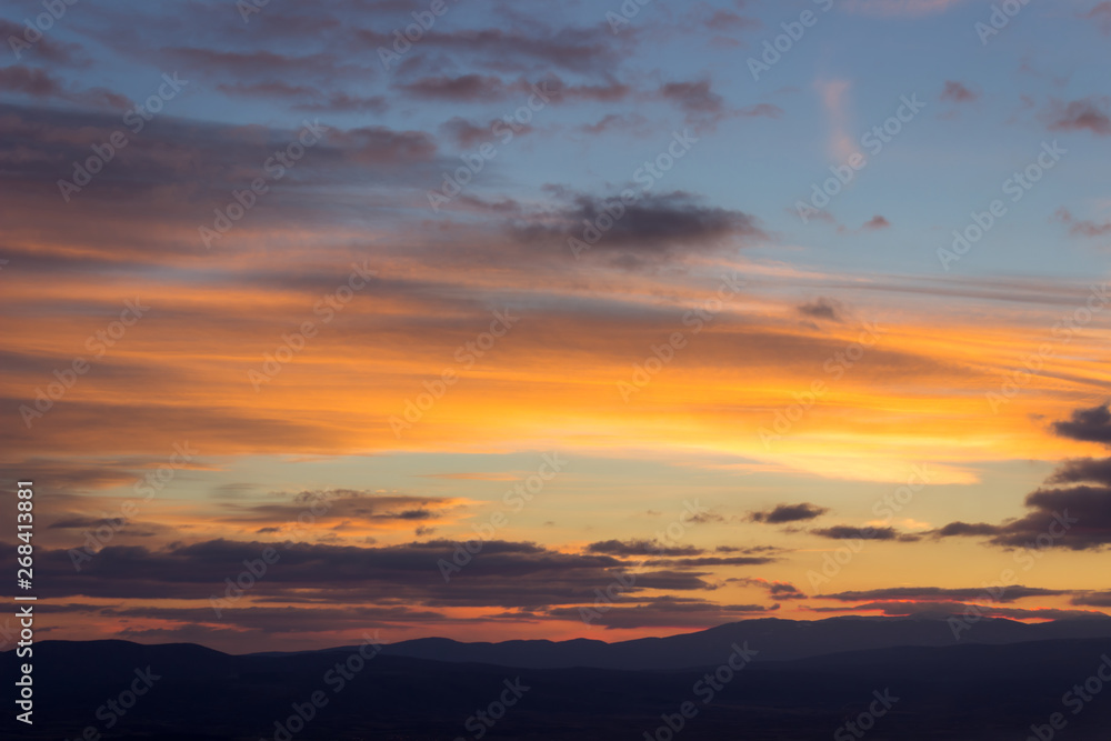 Amazing vivid colors of a sunset sky and clouds and distant horizon mountains
