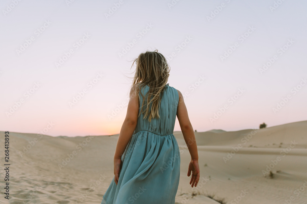 Little girl standing in the desert with her back to the camera
