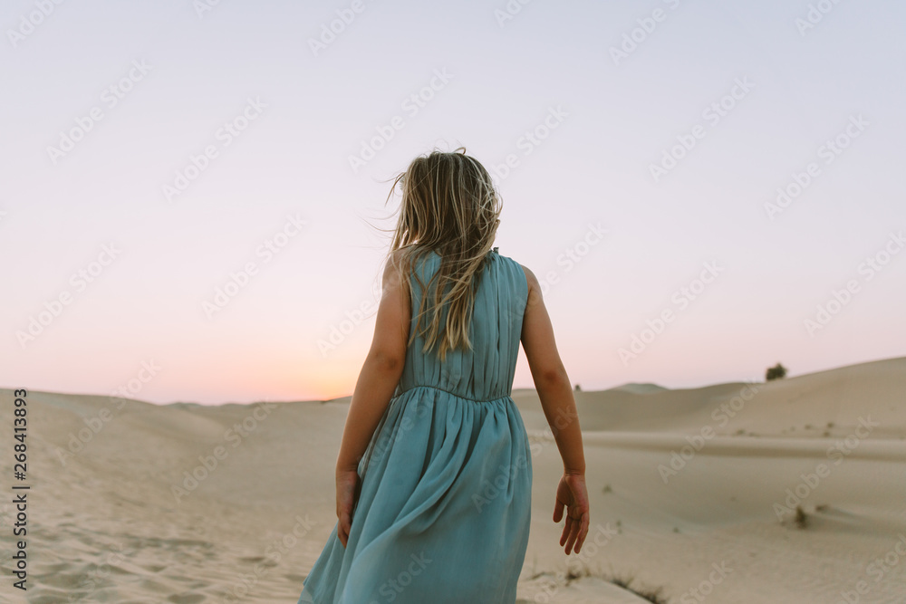 Little girl standing in the desert with her back to the camera Little girl standing in the desert with her back to the camera