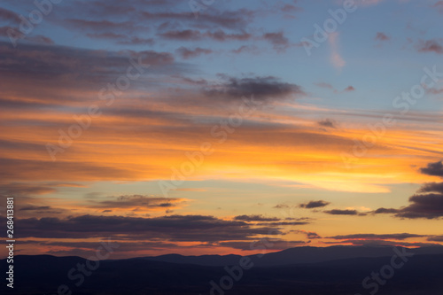 Amazing vivid colors of a sunset sky and clouds and distant horizon mountains