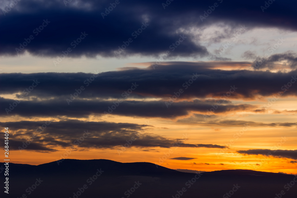 Amazing vivid colors of a sunset sky and clouds and distant horizon mountains