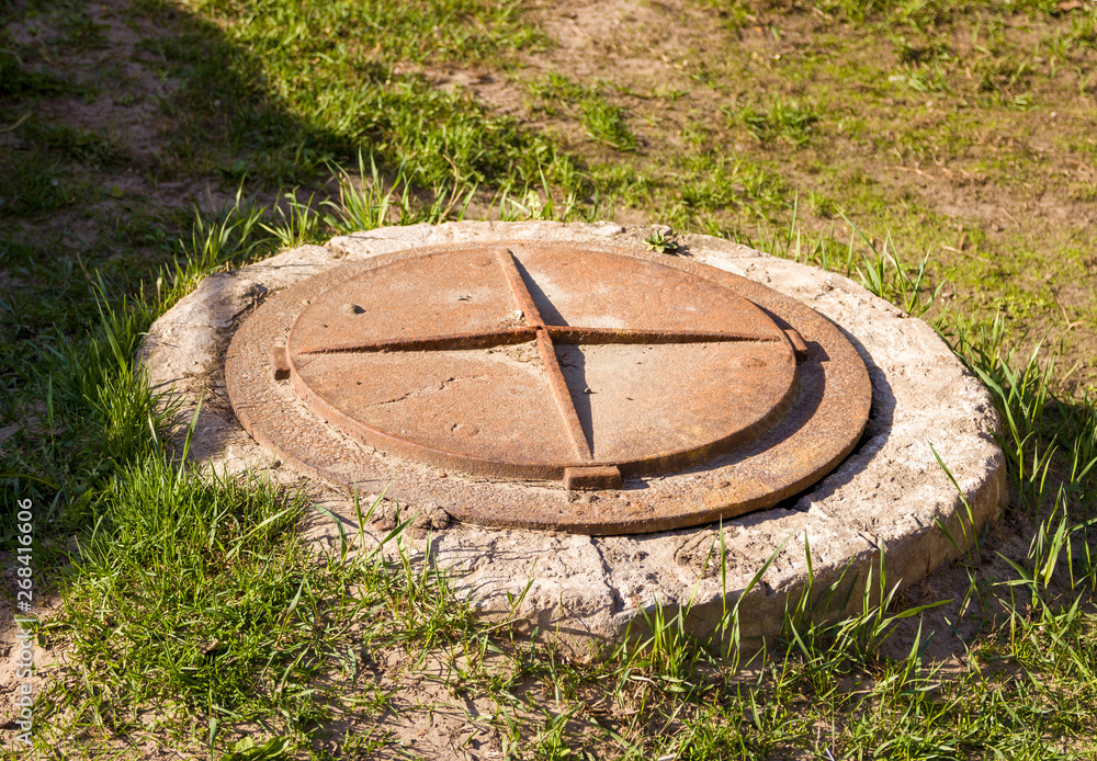 Iron round manhole cover with a cross on it