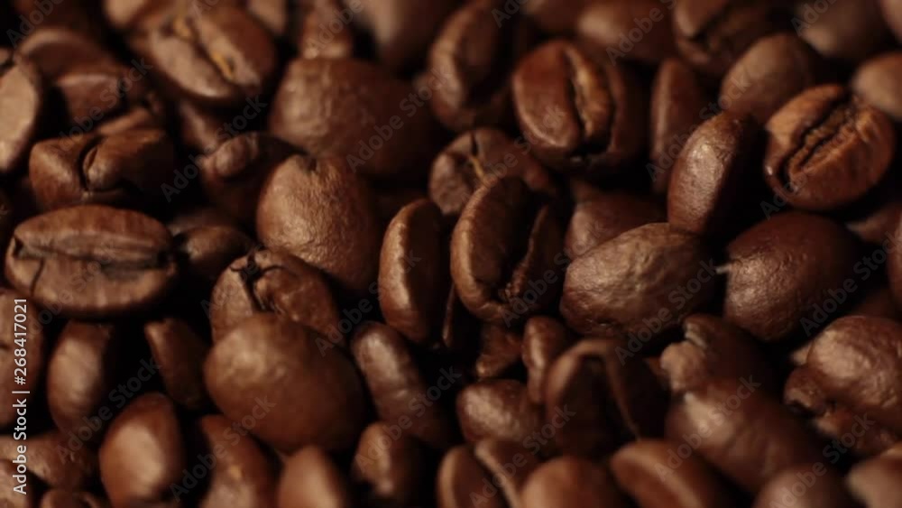 Macro shot of coffee beans rotating along its axis. Beans factory mixing, close up. Roasted coffee bean. Beans of Coffee Raining at Slow Motion. Morning black coffee texture. Macro shot of coffee beans rotating along its axis. Beans factory mixing, close up. Roasted coffee bean. Beans of Coffee Raining at Slow Motion. Morning black coffee texture.