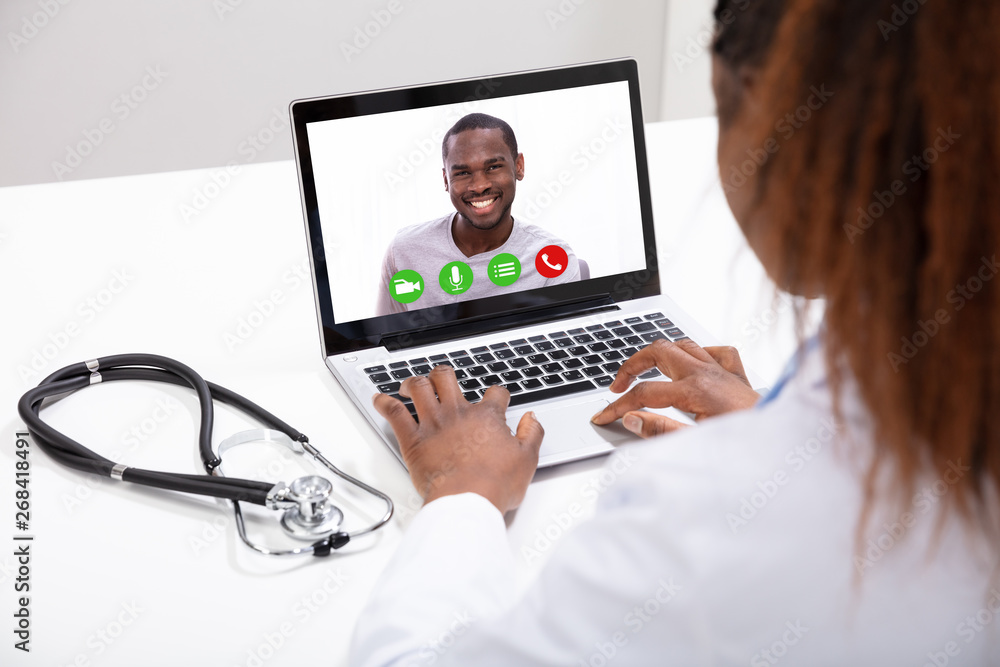 Doctor Video Conferencing With Male Colleague On Computer Doctor Video Conferencing With Male Colleague On Computer