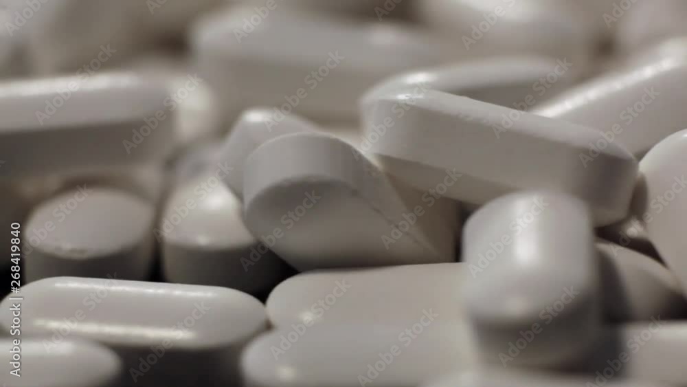 White tablets rotate around its axis. Medical pills rotate around its axis on a black background. Pharmacy antibiotic pills. Medical drugs on table. Pharmaceutical industry. White tablets rotate around its axis. Medical pills rotate around its axis on a black background. Pharmacy antibiotic pills. Medical drugs on table. Pharmaceutical industry.